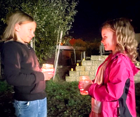 Zwei Personen stehen draußen bei Nacht und halten Getränke.