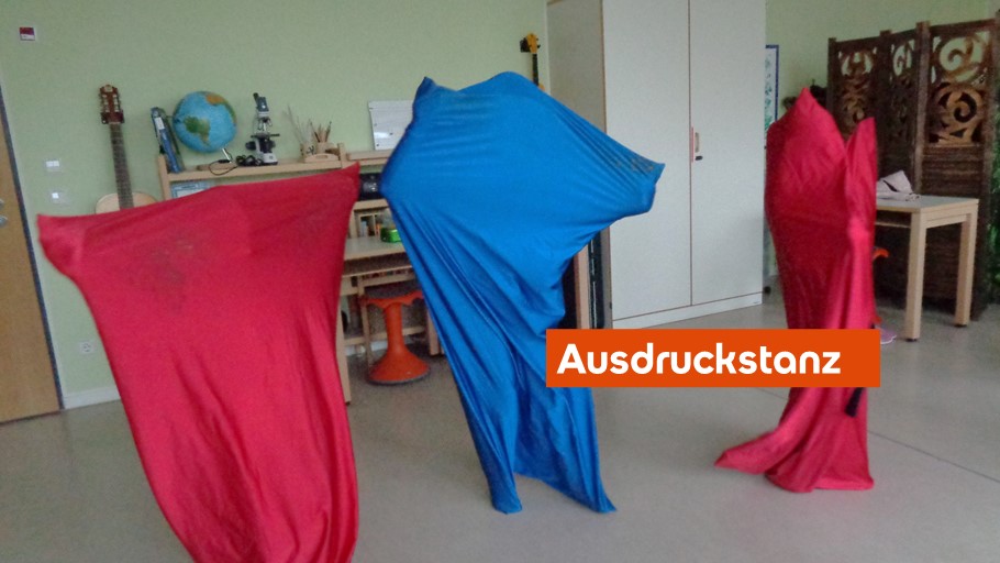 Drei Personen in fließenden roten und blauen Umhängen stehen in einem Raum.