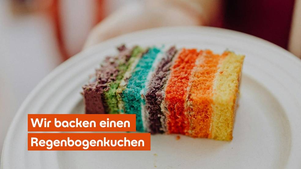 Ein Stück Regenbogenkuchen auf einem weißen Teller.