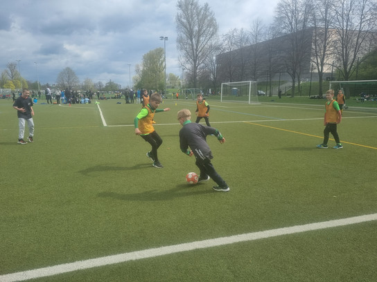 Kinder spielen Fußball auf einem Außenfeld.