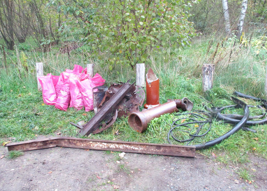 Unordnung im Wald mit Metallteilen und rosa Tüchern.