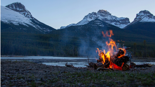 Ein Lagerfeuer vor einem Bergpanorama.