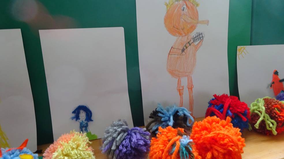 Bild zeigt bunte Wolle und Kinderzeichnungen.