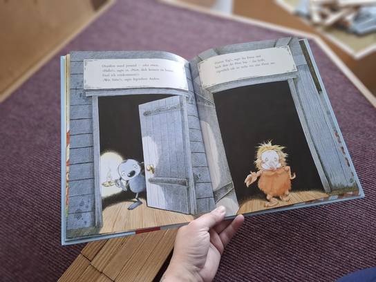 Offenes Kinderbuch mit Illustrationen von Tieren, gehalten von einer Hand.