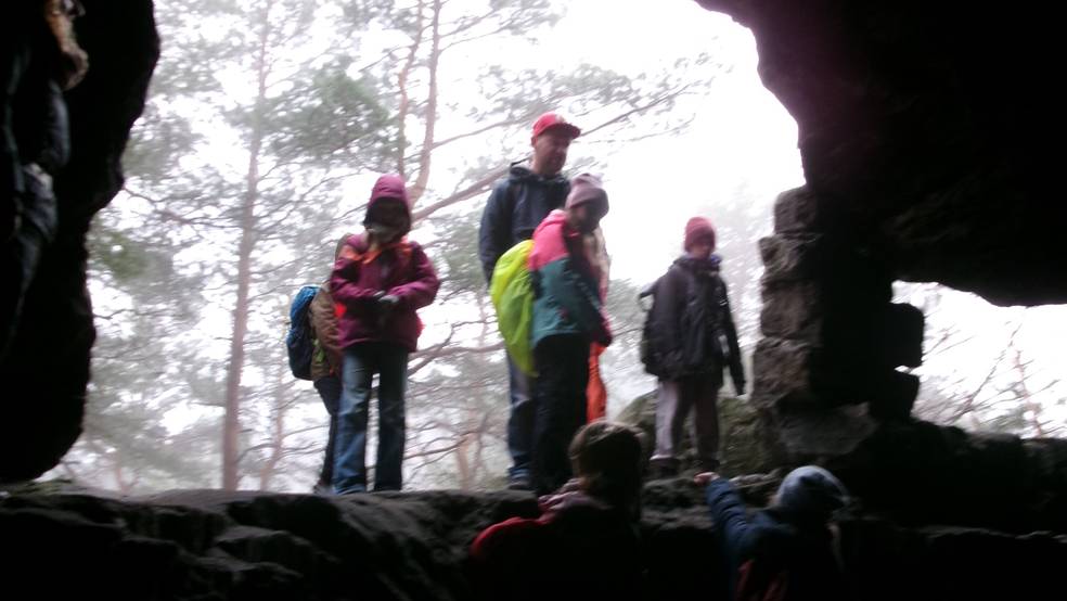 Personen klettern in einer Höhle, sicher mit Seilen gesichert.