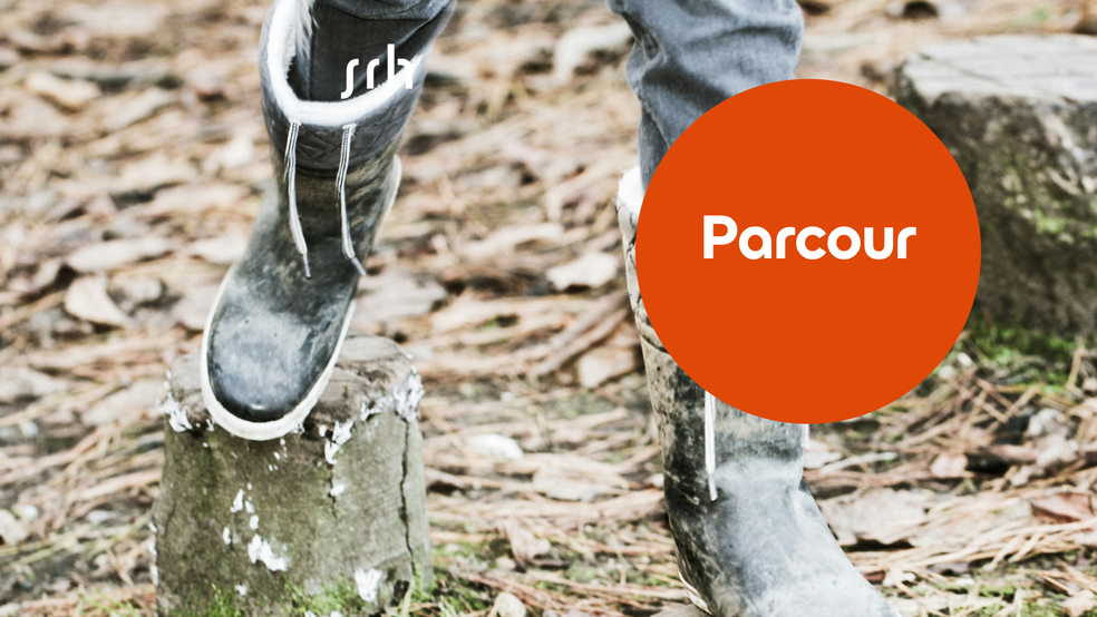 Person steigt über Baumstamm im Wald.